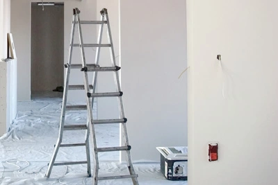 Escalera articulada de aluminio abierta en una obra de interior