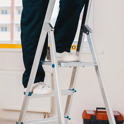 Escalera de tijera de aluminio de tres peldaños con una persona subida